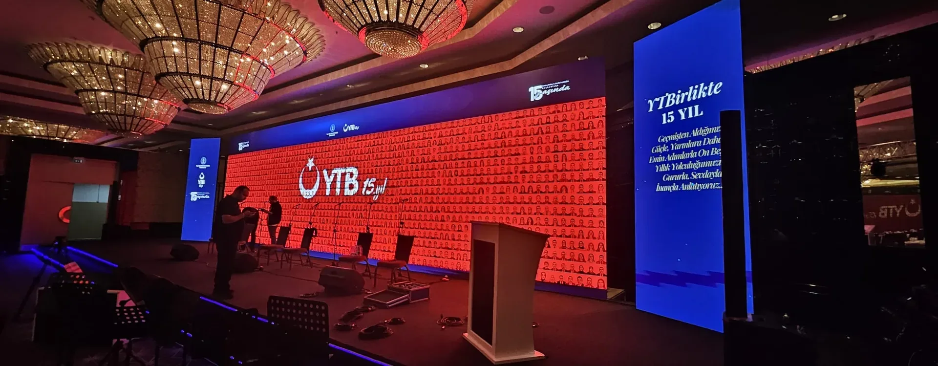 YTB Birlikte 15 Yıl etkinliğinde portrelerden oluşan kırmızı içerikle aydınlatılan geniş LED sahne.
