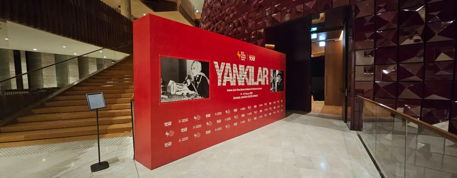 Yankılar etkinliğinin Şule Yüksel Şenler ve Malcolm X görsellerini taşıyan kırmızı karşılama panosu.