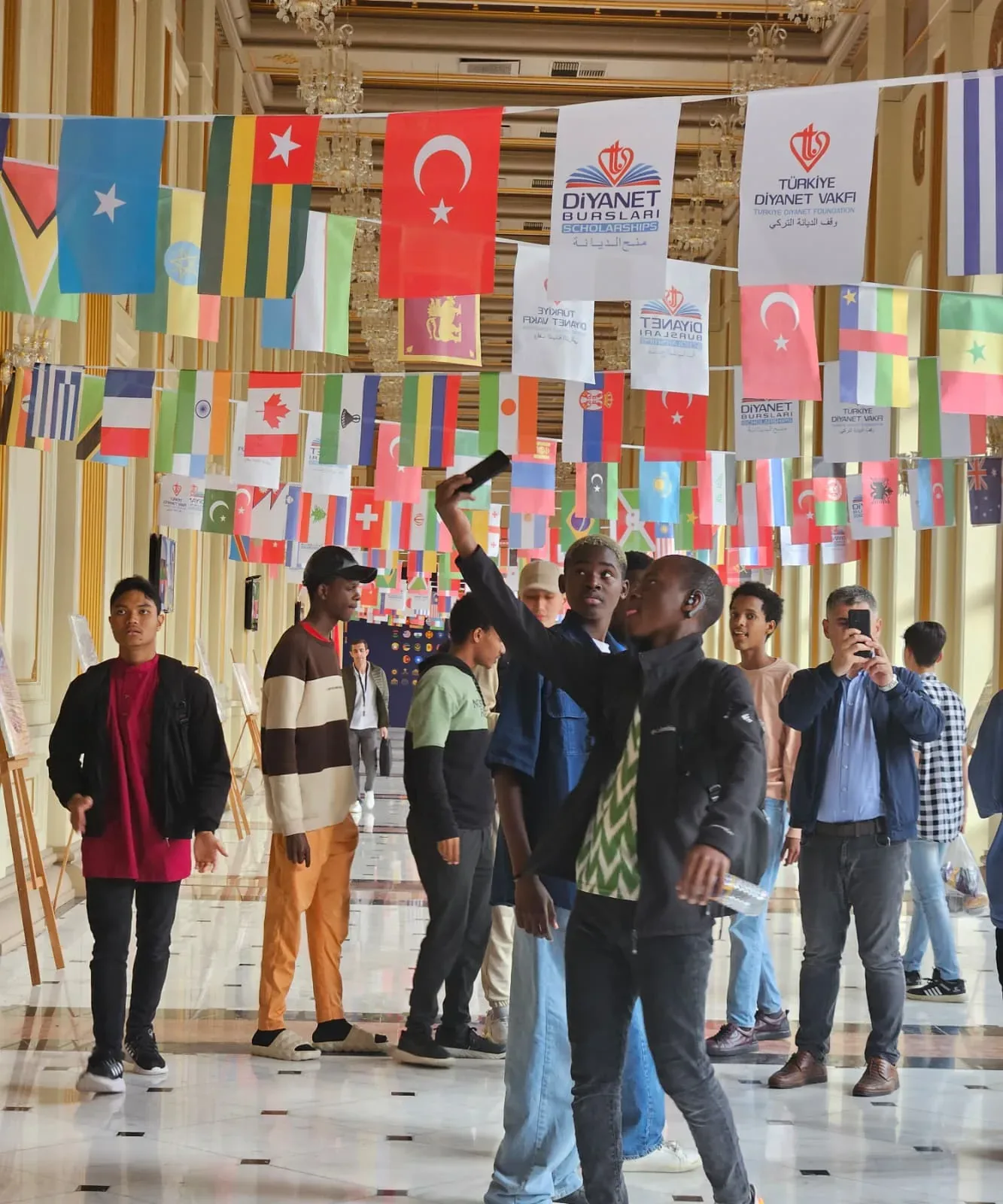 Diyanet Bursları Mezuniyet Programı katılımcılarının ülke bayraklarıyla dekore edilen fuayeyi gezdiği an.